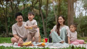A happy Asian family enjoys a summer picnic in a public park. photo