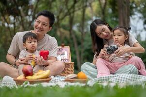 A happy Asian family enjoys a summer picnic in a park, sharing quality time with their little kids. photo