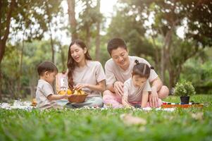 A family enjoys a picnic, dad teaching his daughter to draw while mom plays with their little boy. photo