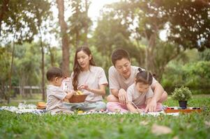 A happy Asian family enjoys a picnic in a park, with dad teaching his daughter to draw on a canvas. photo