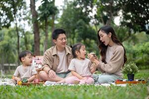A joyful, happy Asian family picnics in a park, enjoying a conversation and eating snacks. photo