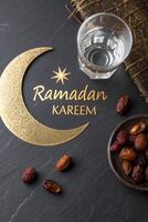Ramadan Kareem business marketing material with moon, dates, and water on dark background photo