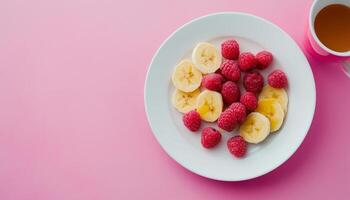 Fresh banana slice and raspberry organic fruit on white plate and pink background photo