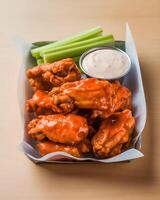 Buffalo chicken wings with celery and sauce in take away box photo