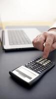 man planning budgets and managing finances. Using a laptop and calculator emphasizes a serious approach to calculations and cost analysis. Concept of financial blogs and consulting materials. video