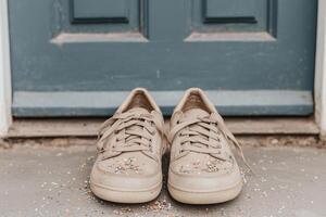 Close-up of beige sneakers sprinkled with confetti, placed on a doorstep with a rustic blue door in the background photo