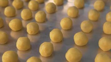 Nastar cookies that are being neatly arranged by a woman's hands wrapped in plastic on a baking sheet, ready to be smeared with egg yolk and baked in the oven with sufficient heat. Camera movement video