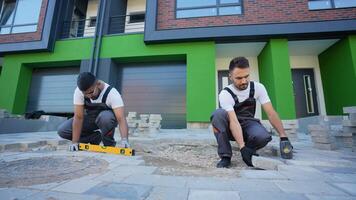 Two diverse construction workers fixing the pavestone on patio video