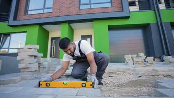 Indian construction worker uses a level tool to precisely align paving stones during installation video