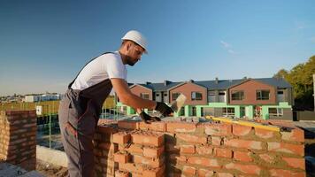 construtor deitado tijolos às uma construção local. construtor deitado tijolos e verificação nível precisão video