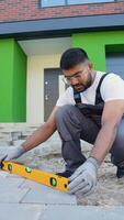 Indian construction worker uses a level tool to precisely align paving stones during installation video