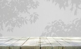 White wooden table top and blurred tree leaf shadow wall background photo