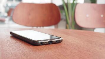 Modern smartphone resting on a wooden table in a cafe video