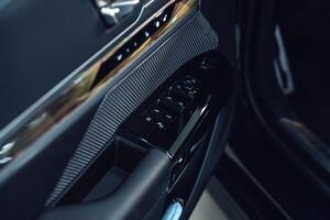 Close-up view of modern car interior door panel with controls and upscale materials photo