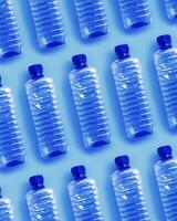 Clear single-use plastic water bottles for water on light blue background close-up geometric pattern, minimal style object, top view row bottle, Pollution, environmental protection, plastic waste photo