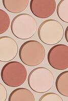 Eyeshadow palette, mix of matte and shimmer shades in pink, nude, red, brown hues. Minimal top view pattern for beauty, makeup, cosmetics themes, Pastel color swatches eyeshade refills round shape photo