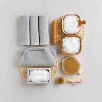 Spa, wellness, bath products as minimal style aesthetic pattern, magnesium salt flakes, folded grey towels, natural brushes, massagers, reusable pads, gray background, top view lifestyle content photo