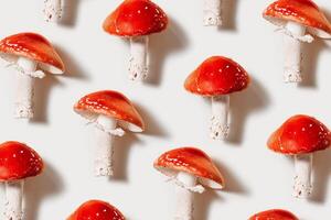 Red mushrooms as minimal pattern on light background, natural textures ad organic beauty, vivid fly agaric with bright red caps and white stems, Creative flat lay still life photo