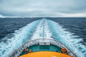 Ship sailing in antarctica leaving a wake in the ocean with snowy mountains in the background photo