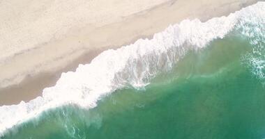 aerial footage, directly above view of the waves breaking on the shore of a beach, sea water texture background concept video