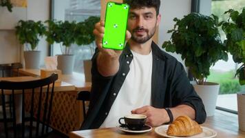 Caucasian man showing mobile phone green screen smartphone advertising display chroma key male thumb up guy cafe visitor client service recommend app mock up businessman smiling business indoor online video