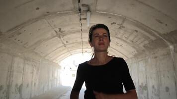 Woman running in a tunnel towards the light. Athlete runs in the tunnel. Active lifestyle. video