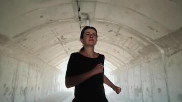 Woman runs to the light at the end of the tunnel. Silhouette of a woman running in an unlit tunnel. video