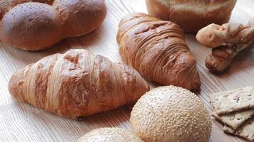 Variety of fresh baked goods on a wooden table, Assortment of croissants, buns, and crackers displayed on a table. video