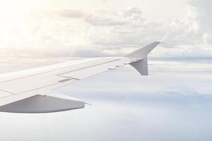 Airplain wing view thrue window in the sky. Clouds and sky as seen through porthole of an aircraft with airplane's wing photo