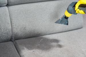 Sofa chemical cleaning with professionally extraction method. Wet textile sofa cleaning. home cleaning service. cleaning sofa with washing suction cleaner closeup. photo