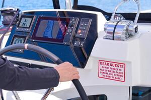 A person is steering a yacht with a control panel showing the boat s position on a map. The panel also has various other buttons and switches for controlling the boat. photo