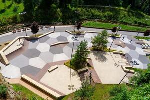 The skatepark in Luxembourg offers a vibrant space for skateboarding enthusiasts, surrounded by lush trees and the serene flow of a nearby river, creating an ideal setting for all skill levels. photo