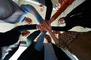 A group of business professionals, captured from a low angle, holding hands to symbolize unity and teamwork. photo