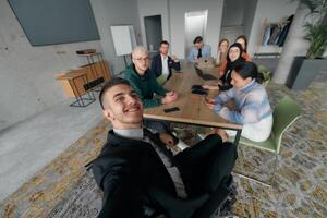A group of business professionals taking a selfie during a break in an office meeting, capturing a moment of teamwork and collaboration in a modern workplace photo