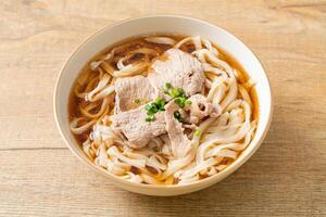 homemade udon noodles with pork in soy or shoyu soup in bowl photo