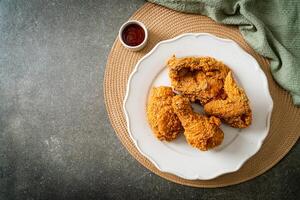 fried chicken with ketchup on plate on dark background photo