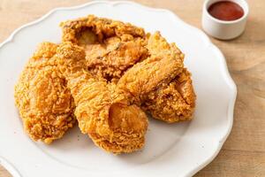 fried chicken with ketchup on plate on wood background photo