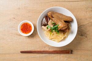 dried noodles with braised duck in white bowl on wood background photo