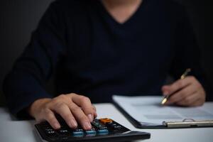 A person is using a calculator on a desk photo