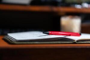 Close-up of Notebook with Red Pen and Candle photo