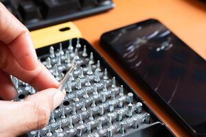 A person is using a screwdriver to remove a cell phone photo