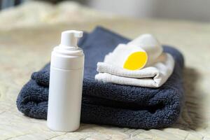 A bottle of deodorant and a towel on a bed photo