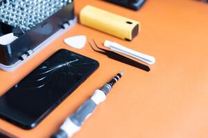 A broken cell phone sitting on top of a table with tools photo