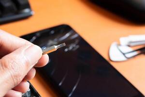 A person is holding a small screwdriver to repair a broken cell phone photo