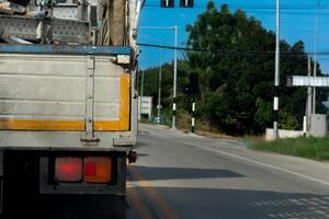 Beside of truck car open brake signal. Stop on the empty road. Front of the car is an intersection with traffic lights. with tree and grass side of road. under blue sky. photo