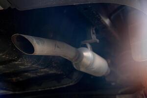 Abstract of car exhaust pipe that extends from under the car. Under view of car in the dark tone. photo