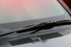 Windshield wipers are folded and stored on the windshield of the car. Clean car windshields and hoods without rain stains. photo