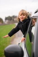 The small boy, excited and carefree, leans out of the window, enjoying the scenery on a road trip. photo