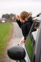 The boy, excited and carefree, leans out of the window, enjoying the scenery on a road trip. photo