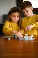 Brother and sister compete playfully in a lively board game at home photo